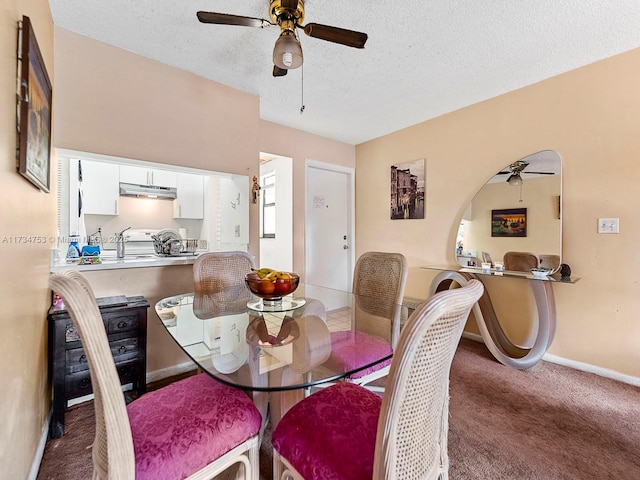 dining area featuring ceiling fan, sink, carpet floors, and a textured ceiling