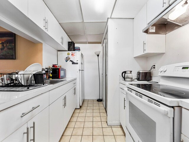 kitchen featuring white cabinetry, white appliances, and light tile patterned flooring