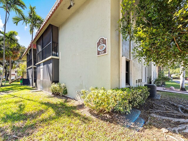 view of side of property with a sunroom, central AC unit, and a lawn