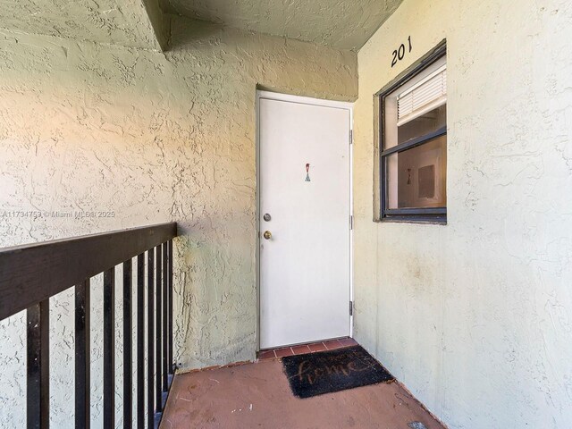 view of exterior entry with a balcony