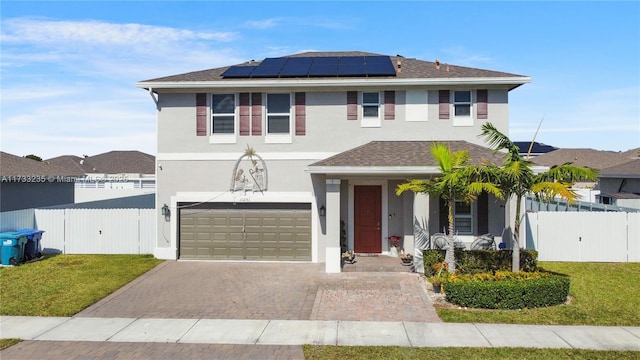 front of property featuring a garage, a front lawn, and solar panels