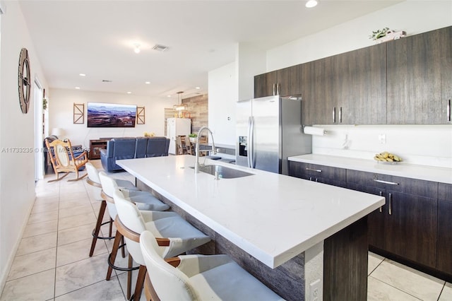 kitchen with an island with sink, sink, a breakfast bar, and stainless steel fridge with ice dispenser