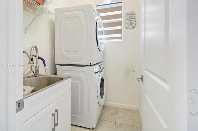 clothes washing area featuring light tile patterned floors, sink, and stacked washing maching and dryer