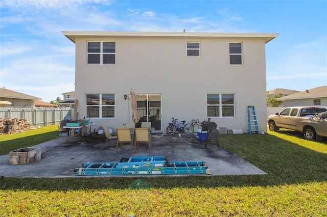 rear view of property with a fire pit, a patio area, and a lawn