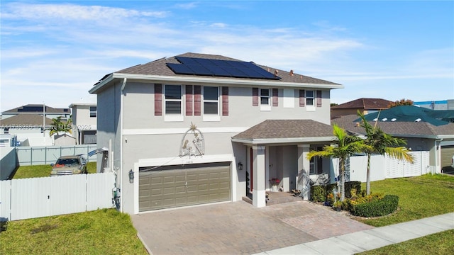 view of front property featuring a garage, a front yard, and solar panels