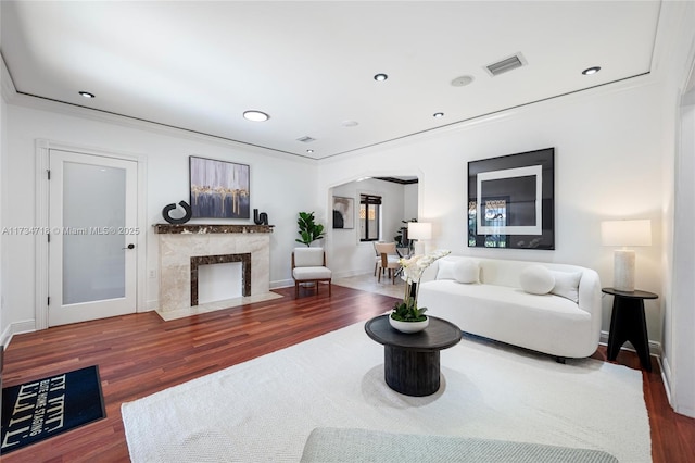 living room featuring dark hardwood / wood-style flooring, crown molding, and a high end fireplace