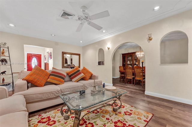 living room featuring ceiling fan with notable chandelier, ornamental molding, and hardwood / wood-style floors