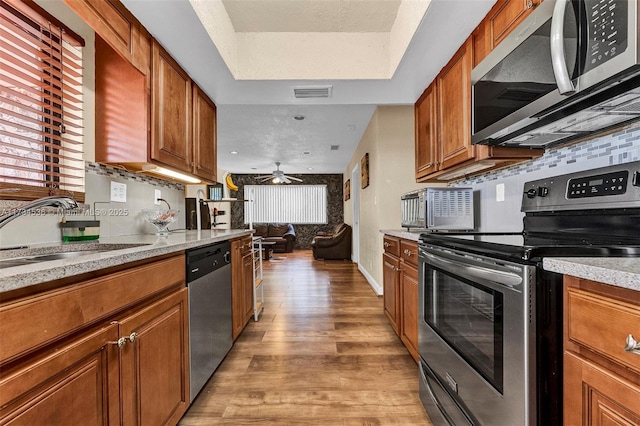 kitchen featuring sink, appliances with stainless steel finishes, ceiling fan, light hardwood / wood-style floors, and decorative backsplash