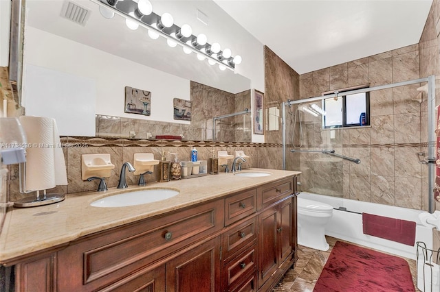 full bathroom with tile walls, backsplash, enclosed tub / shower combo, vanity, and toilet