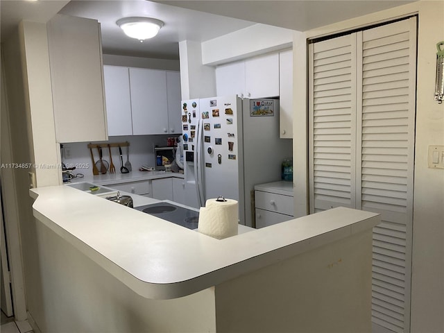 kitchen featuring white cabinetry, a breakfast bar, kitchen peninsula, and white fridge with ice dispenser