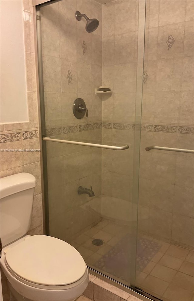 bathroom featuring toilet, tile walls, and walk in shower