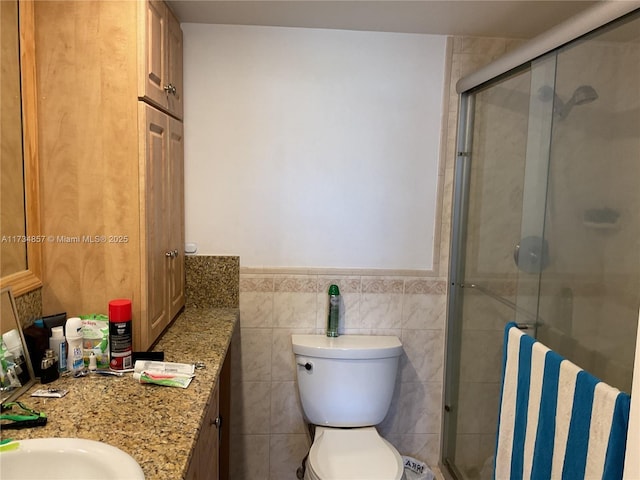 bathroom featuring tile walls, vanity, a shower with door, and toilet