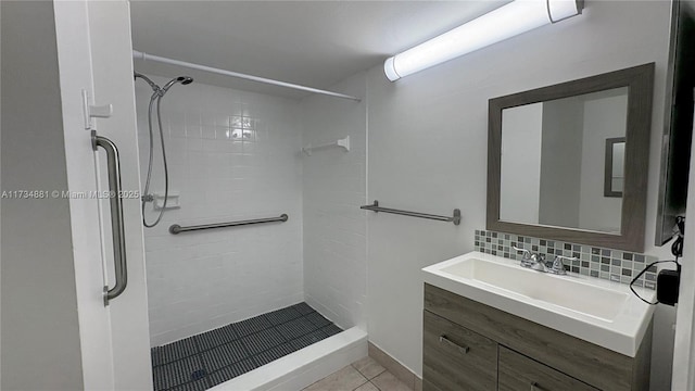 bathroom featuring tile patterned flooring, vanity, decorative backsplash, and tiled shower