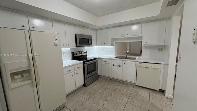 kitchen with sink, appliances with stainless steel finishes, white cabinetry, a textured ceiling, and light tile patterned flooring