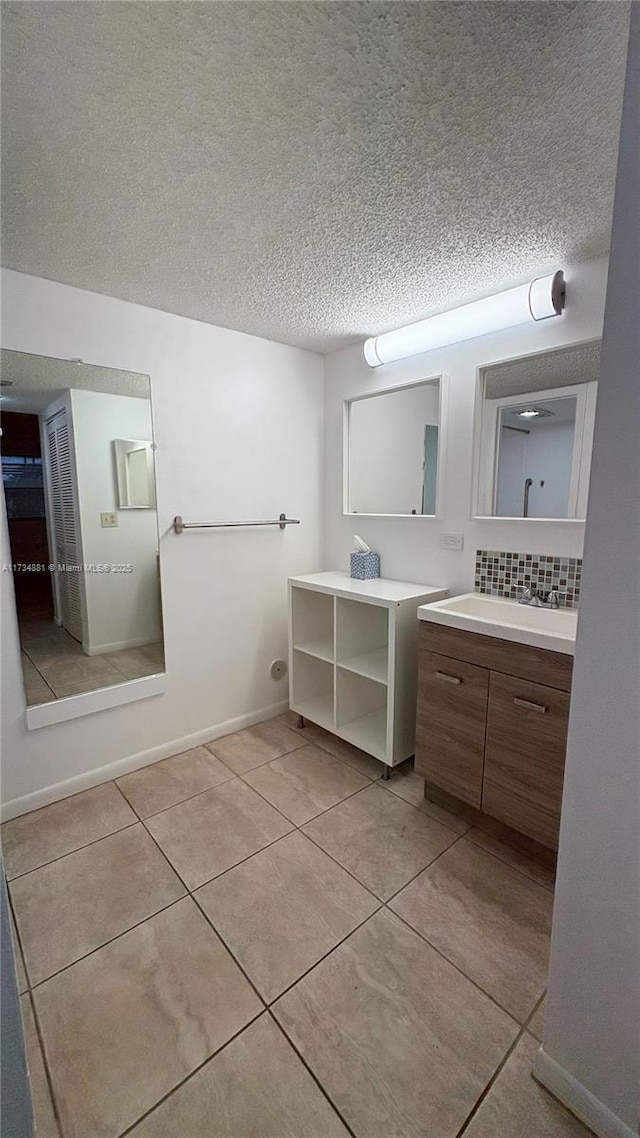 bathroom featuring tile patterned flooring, vanity, backsplash, and a textured ceiling