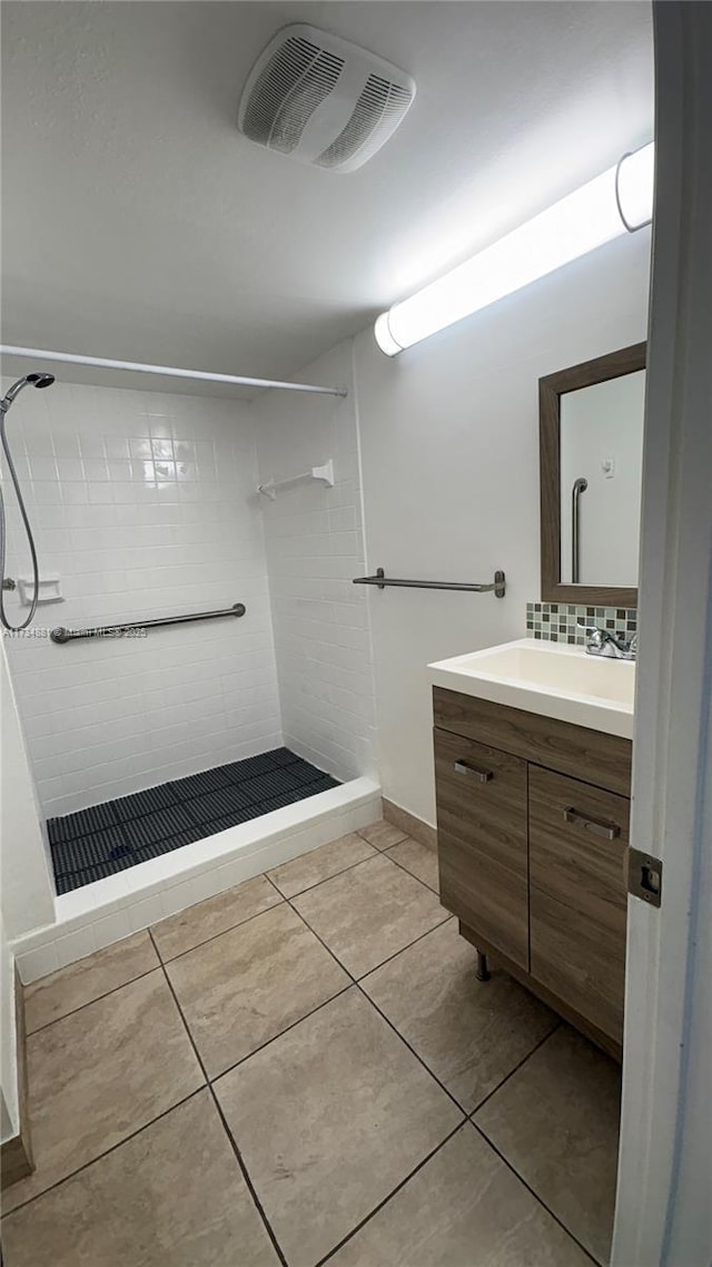 bathroom with tasteful backsplash, tiled shower, vanity, and tile patterned flooring