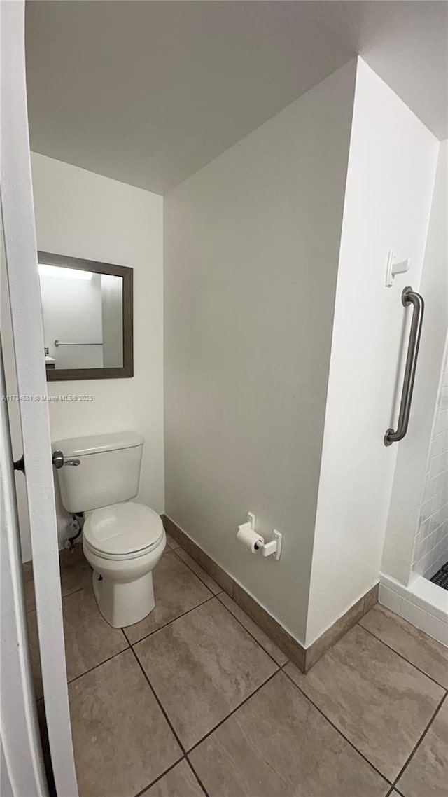 bathroom with tile patterned flooring, walk in shower, and toilet