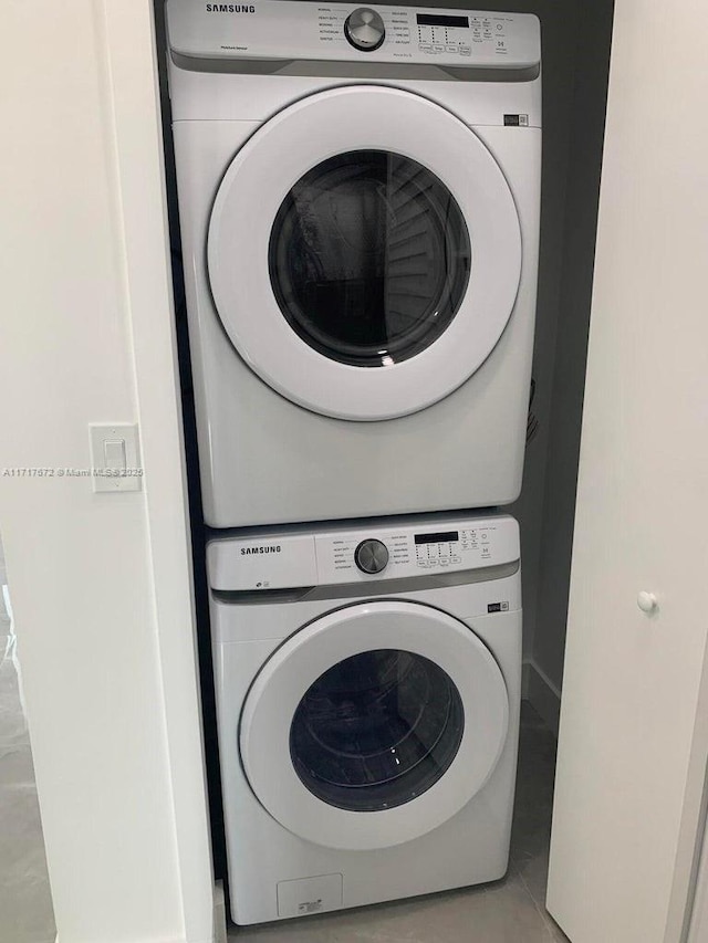 washroom with stacked washing maching and dryer and light tile patterned floors