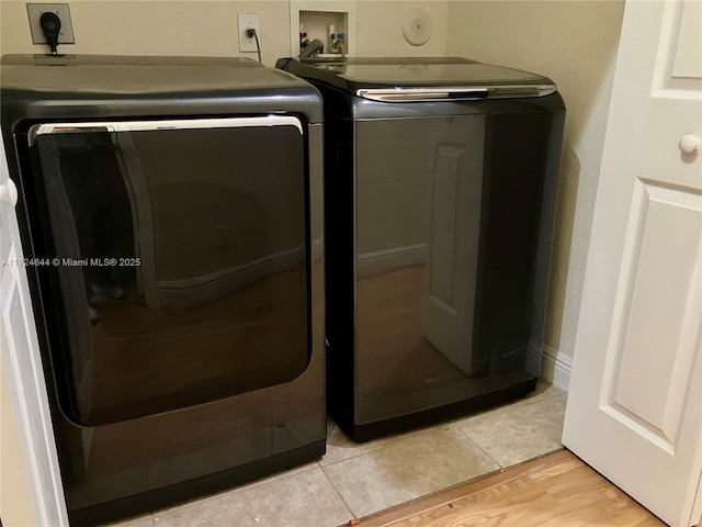 clothes washing area with washer and dryer and light tile patterned floors