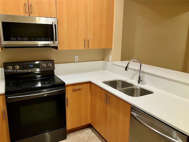 kitchen with appliances with stainless steel finishes, sink, and light tile patterned floors