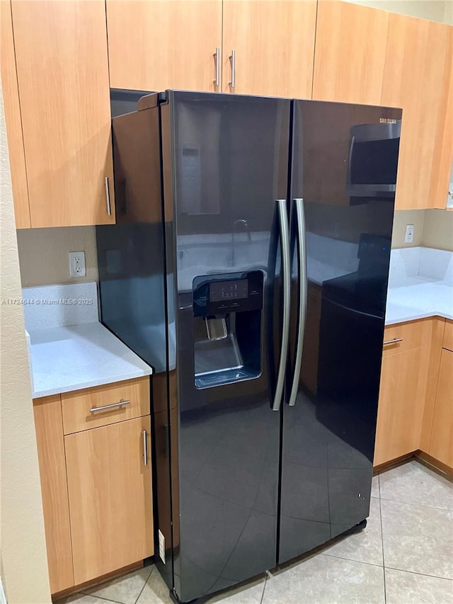 kitchen with black refrigerator with ice dispenser and light tile patterned floors