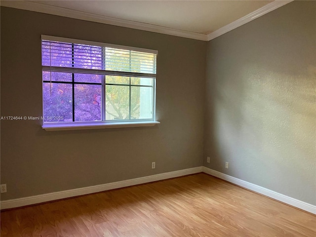 empty room with ornamental molding and light hardwood / wood-style floors