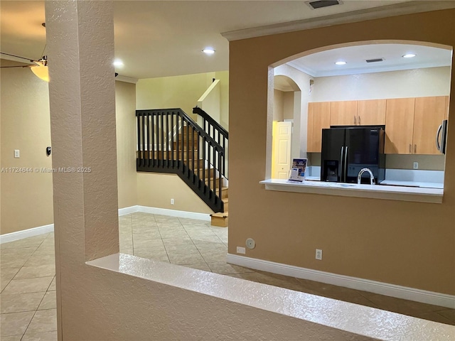 kitchen featuring light tile patterned flooring, ornamental molding, black fridge with ice dispenser, and light brown cabinets