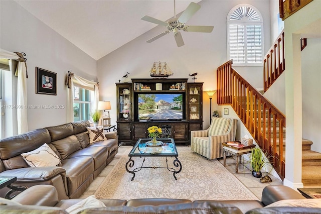 tiled living room with ceiling fan and a high ceiling