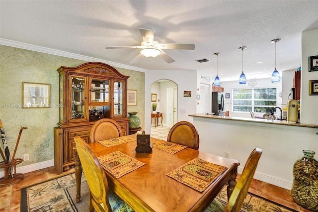 dining area featuring light tile patterned floors, ornamental molding, a textured ceiling, and ceiling fan