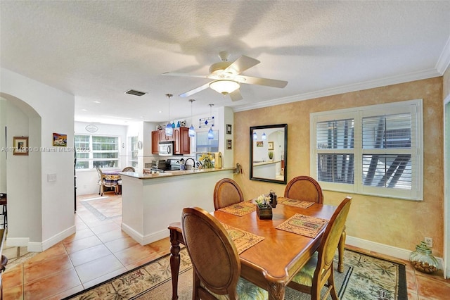 dining area featuring ceiling fan, crown molding, light tile patterned floors, and a textured ceiling