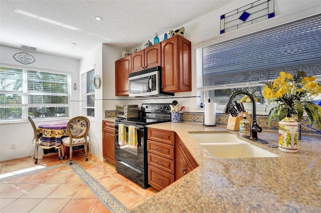 kitchen with light tile patterned floors, sink, a textured ceiling, and electric range