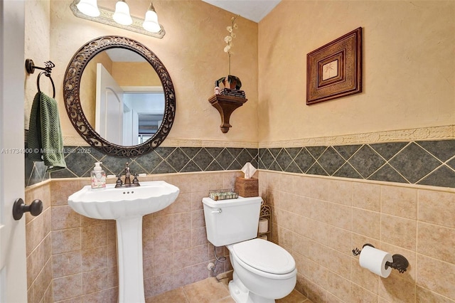 bathroom featuring tile patterned floors, toilet, and tile walls