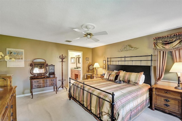 bedroom with ensuite bathroom, light carpet, ceiling fan, and a textured ceiling