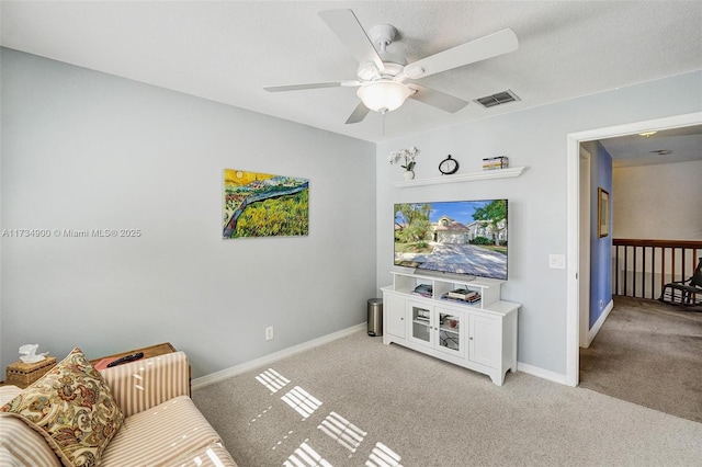 carpeted living room featuring ceiling fan and a textured ceiling