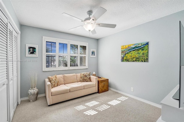 carpeted living room featuring ceiling fan and a textured ceiling