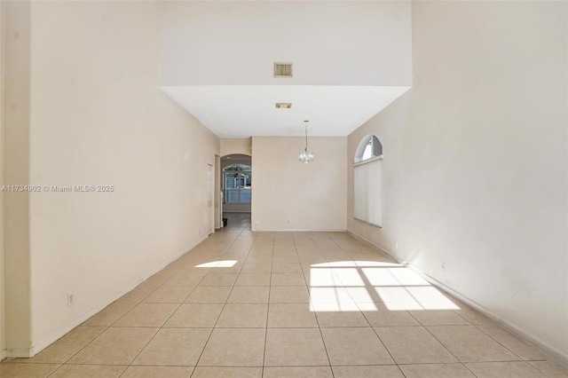 unfurnished room with light tile patterned floors and a notable chandelier