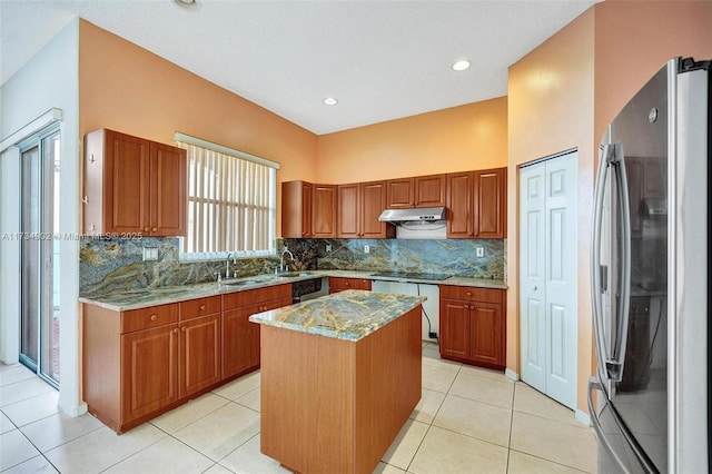 kitchen featuring light tile patterned flooring, appliances with stainless steel finishes, decorative backsplash, a center island, and light stone counters