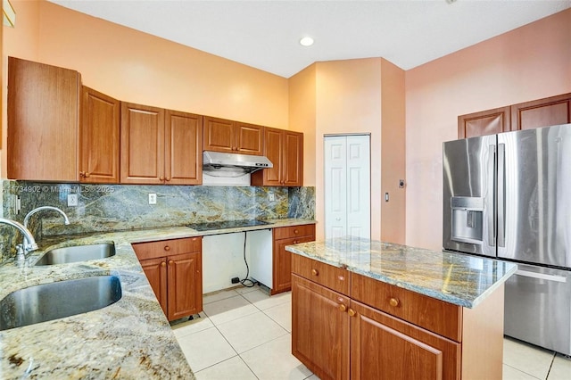 kitchen featuring a center island, light stone countertops, sink, and stainless steel fridge