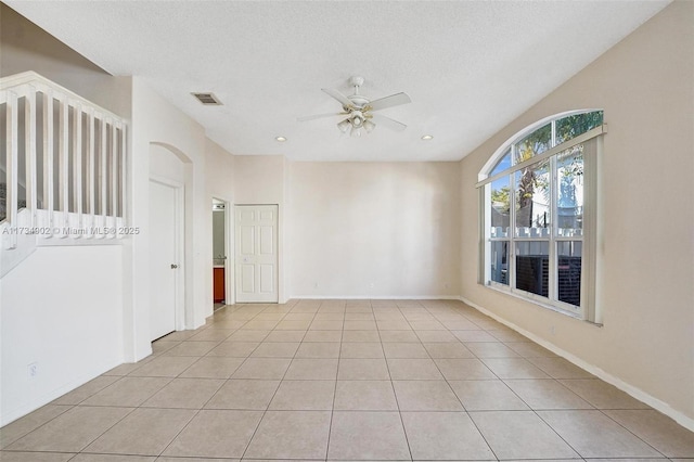 spare room featuring ceiling fan, a textured ceiling, and light tile patterned floors