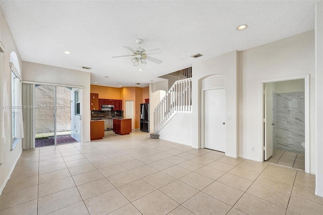 unfurnished living room featuring light tile patterned flooring, ceiling fan, and a textured ceiling