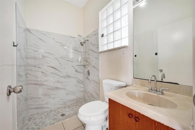 bathroom with vanity, toilet, and a tile shower