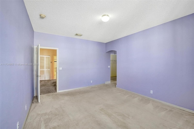 unfurnished room with light carpet and a textured ceiling