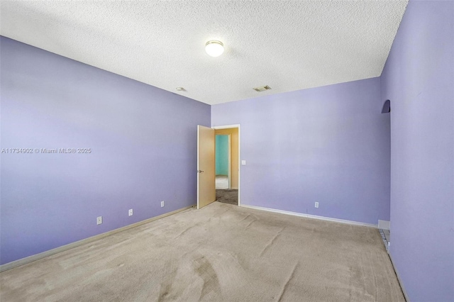 unfurnished room featuring light colored carpet and a textured ceiling