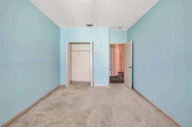 unfurnished bedroom featuring light colored carpet, a textured ceiling, and a closet