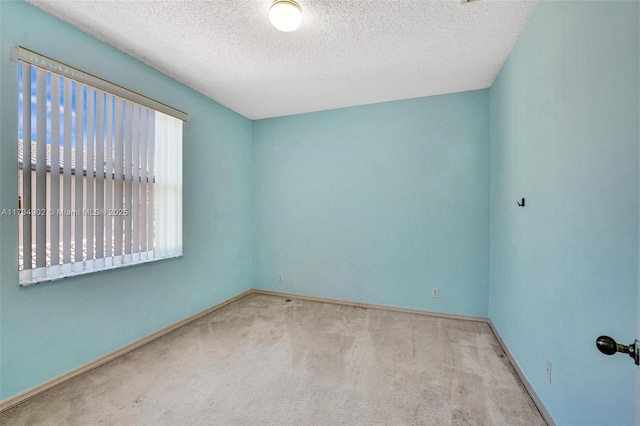 unfurnished room with light colored carpet and a textured ceiling