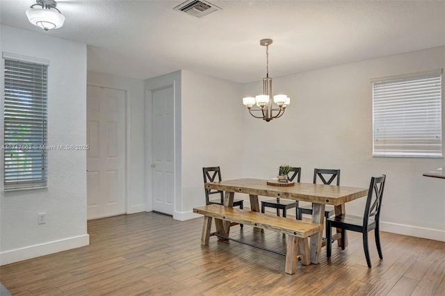 dining space with hardwood / wood-style floors and a notable chandelier