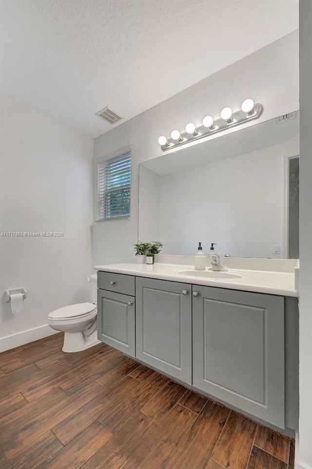 bathroom featuring wood-type flooring, vanity, a textured ceiling, and toilet