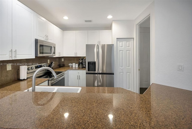 kitchen with appliances with stainless steel finishes, sink, white cabinets, and backsplash