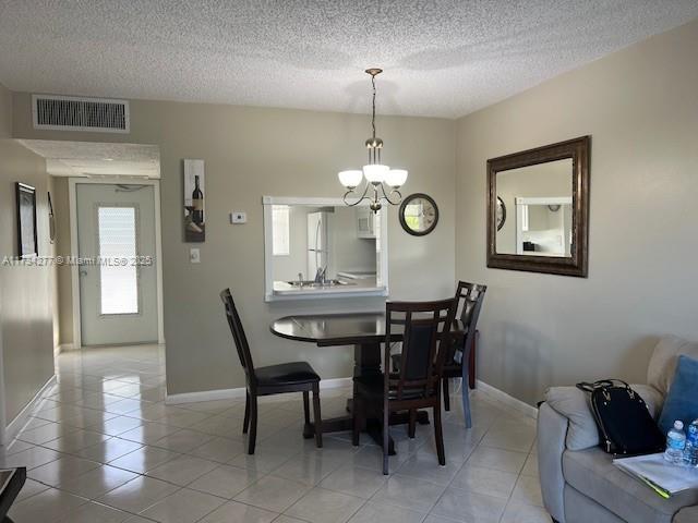 tiled dining space featuring a textured ceiling and a notable chandelier