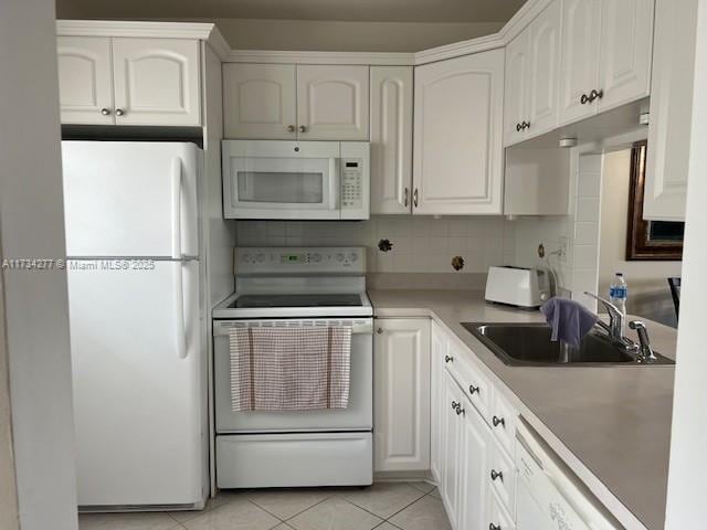 kitchen featuring sink, white appliances, light tile patterned floors, tasteful backsplash, and white cabinets